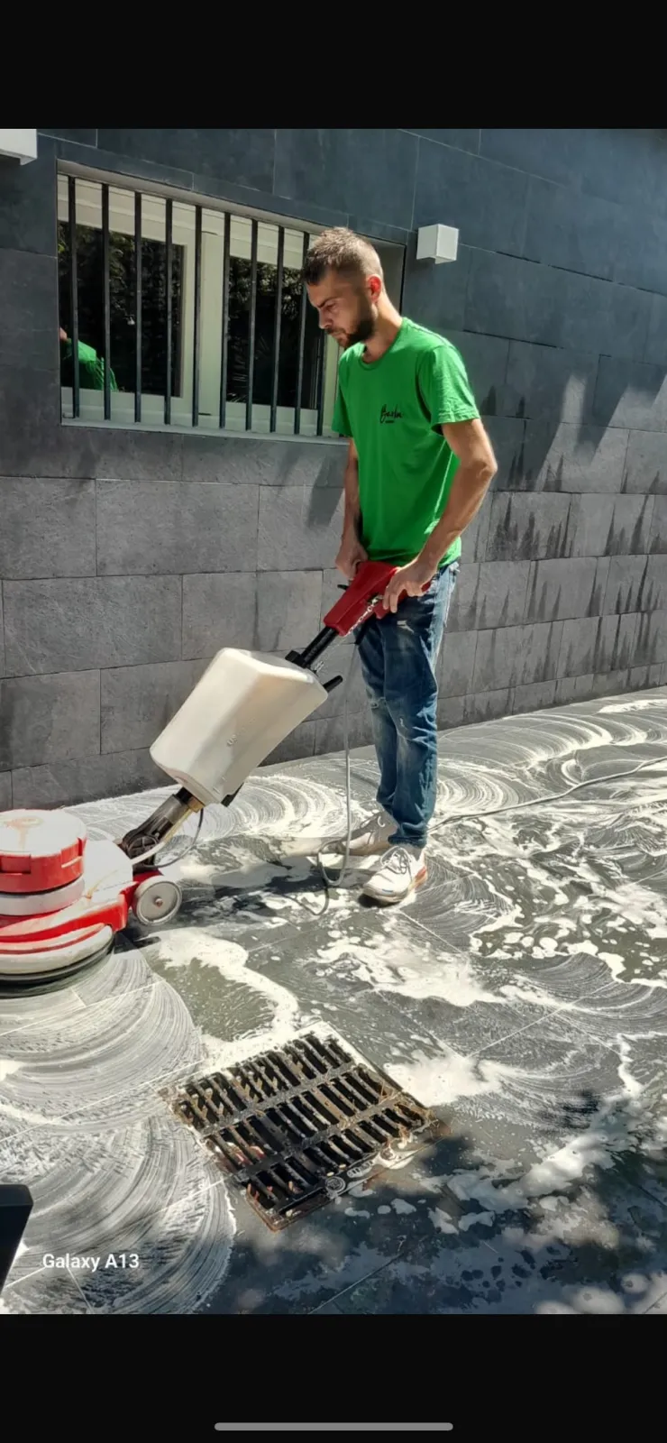 Operatore Barbu Service lava un pavimento esterno con monospazzola e detergente schiumogeno
