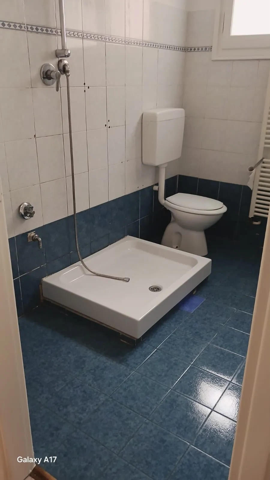 Lo stesso bagno dopo l'intervento: piastrelle blu, piatto doccia e sanitari puliti