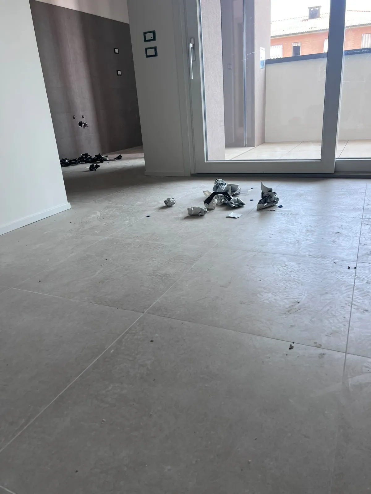 Soggiorno con pavimento in gres prima della pulizia: polvere e residui di cantiere